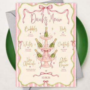 Può includere: Un cartoncino rettangolare per il menu delle bevande con un bordo a righe rosa e bianche, bordi smerlati verdi e fiocchi rosa. Il centro mostra un'illustrazione di una torre di champagne a tre livelli. Il testo include Drinks Menu, Bubbles, Reds, Whites, Cocktails, Non Alcoholic, After Dinner e la data 12.08.26.