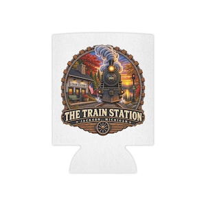 Könnte beinhalten: Ein weißer Dosenkühler aus Schaumstoff mit einer kreisförmigen Grafik einer Dampflokomotive, die in einen Bahnhof einfährt. Der Text lautet THE TRAIN STATION JACKSON, MICHIGAN mit dem Jahr 2025 auf dem Zug, einem Gebäude und einer US-Flagge.
