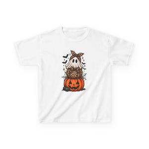 May include: A white t-shirt featuring a graphic of a ghost wearing a leopard print bow, sitting on a leopard print pumpkin, which is stacked on top of a large orange jack-o'-lantern. The design includes black bats and spider webs.