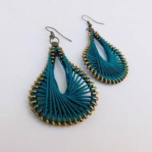 May include: Teal blue and gold earrings with a woven design. The earrings are teardrop shaped and have a dangling design.