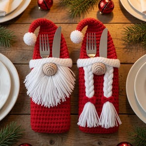 May include: Two red crochet cutlery holders shaped like Christmas gnomes. One features a white yarn beard, the other has two white braided pigtails with small red bows. Both have a white pom-pom on the hat tip and hold a silver fork and knife.