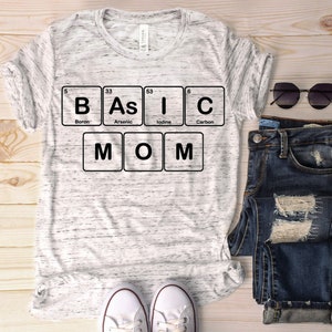 May include: A white t-shirt with a black graphic of the periodic table elements spelling out "BASIC MOM".