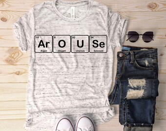 Könnte beinhalten: Ein weißes T-Shirt mit einer schwarzen Grafik des Periodensystems der Elemente, die "Ar O U Se" buchstabiert. Die Grafik enthält die Elementsymbole und -namen: Argon, Sauerstoff, Uran und Selen.