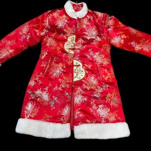 May include: A red Chinese-style coat with a floral pattern and white faux fur trim. The coat features a mandarin collar, decorative frog closures, and long sleeves. The coat is approximately 40 inches long.