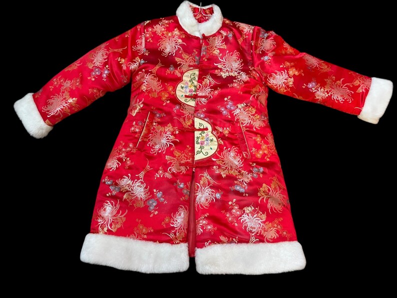 May include: A red Chinese-style coat with a floral pattern and white faux fur trim. The coat features a mandarin collar, decorative frog closures, and long sleeves. The coat is approximately 40 inches long.
