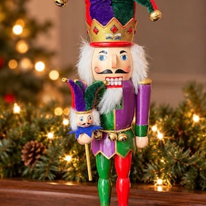 May include: A jester nutcracker figurine wearing a gold crown with red accents, a purple and green velvet hat with gold bells, and a colorful outfit. The figure holds a miniature jester staff and stands on a round purple base with green trim.