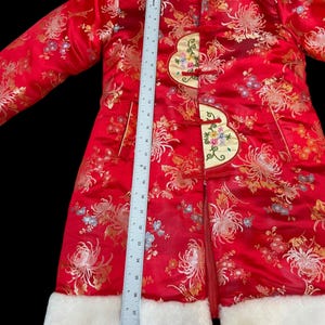 May include: A red Chinese-style coat with a floral pattern and white faux fur trim. The coat features decorative frog closures and a white fur collar. The coat measures approximately 30 inches in length.