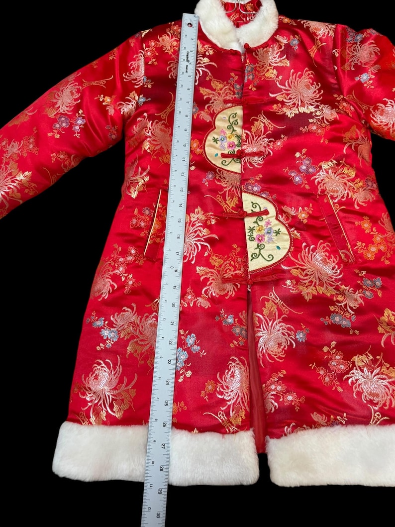 May include: A red Chinese-style coat with a floral pattern and white faux fur trim. The coat features decorative frog closures and a white fur collar. The coat measures approximately 30 inches in length.