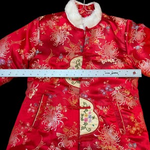 May include: Red satin jacket with floral embroidery and a white faux fur collar. The jacket features a decorative embroidered panel on the front and measures approximately 18 inches across the chest.