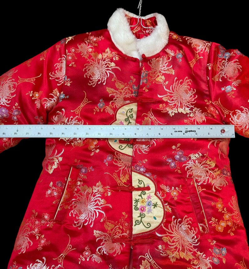 May include: Red satin jacket with floral embroidery and a white faux fur collar. The jacket features a decorative embroidered panel on the front and measures approximately 18 inches across the chest.