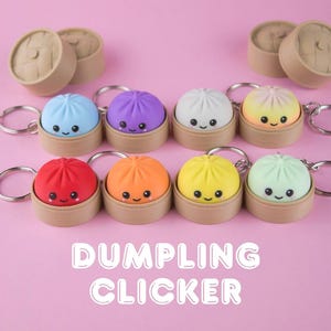 May include: A collection of eight colorful dumpling keychains, each featuring a smiling face and a small metal ring. The dumplings are housed in individual brown circular containers. The text DUMPLING CLICKER is displayed in white letters at the bottom.
