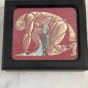 May include: A framed artwork featuring a large, stylised gold figure kneeling on a deep red background. A smaller, slender figure with long white hair and blue accents stands in front, connected by a thin chain to the larger figure's ankle.