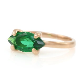 Puede incluir: Un anillo de oro con una piedra preciosa verde en forma de marquesa.