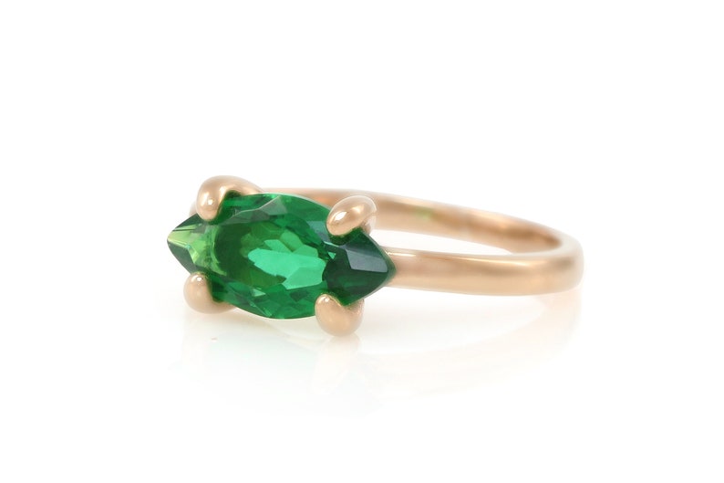 Puede incluir: Un anillo de oro con una piedra preciosa verde en forma de marquesa.