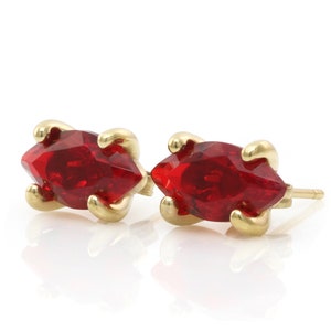 May include: A pair of gold earrings with red marquise-shaped gemstones.