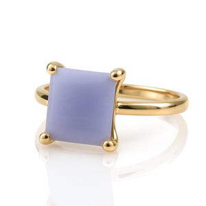 May include: A gold ring with a square, lavender-colored gemstone set in a prong setting.