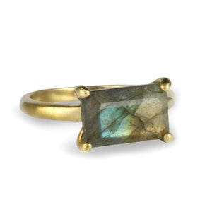 May include: A gold ring featuring a large, rectangular, iridescent labradorite gemstone.