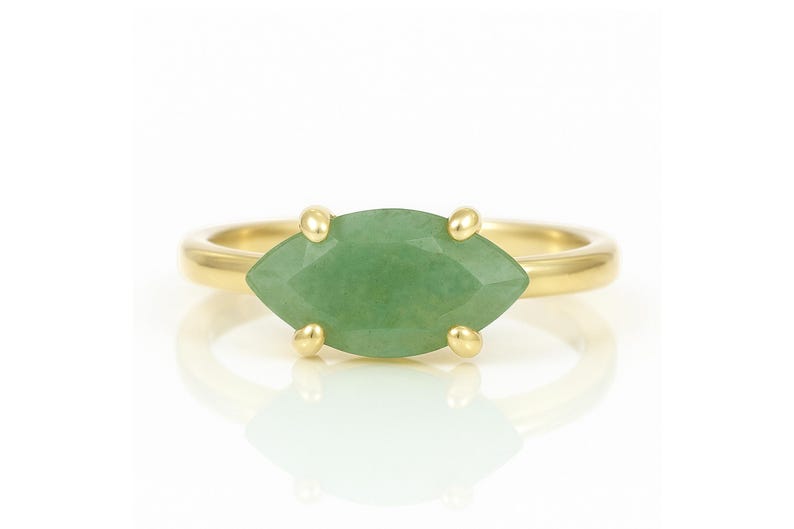 May include: A gold ring with a marquise-shaped green gemstone.