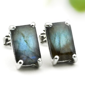 May include: A pair of silver earrings with rectangular labradorite gemstones. The stones have a dark blue and green iridescent sheen.