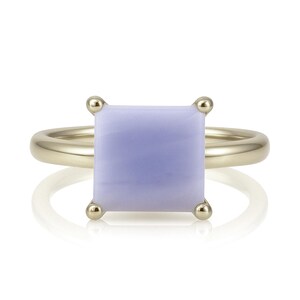 May include: A gold ring with a square, lavender-colored gemstone.