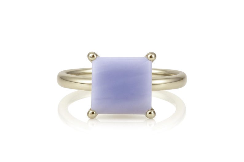 May include: A gold ring with a square, lavender-colored gemstone.