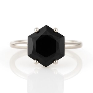 May include: A silver ring with a black hexagonal gemstone.