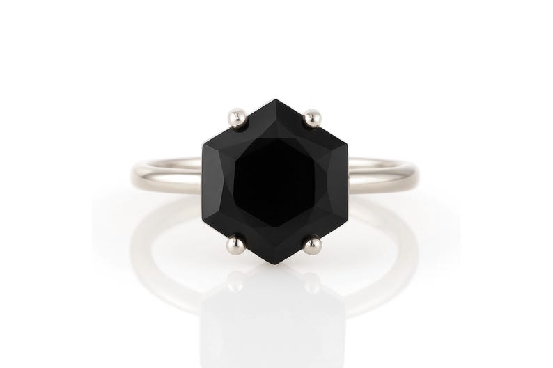 May include: A silver ring with a black hexagonal gemstone.