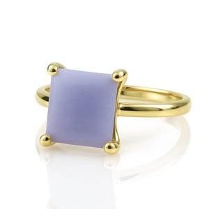 May include: A gold ring with a square, lavender-colored gemstone.