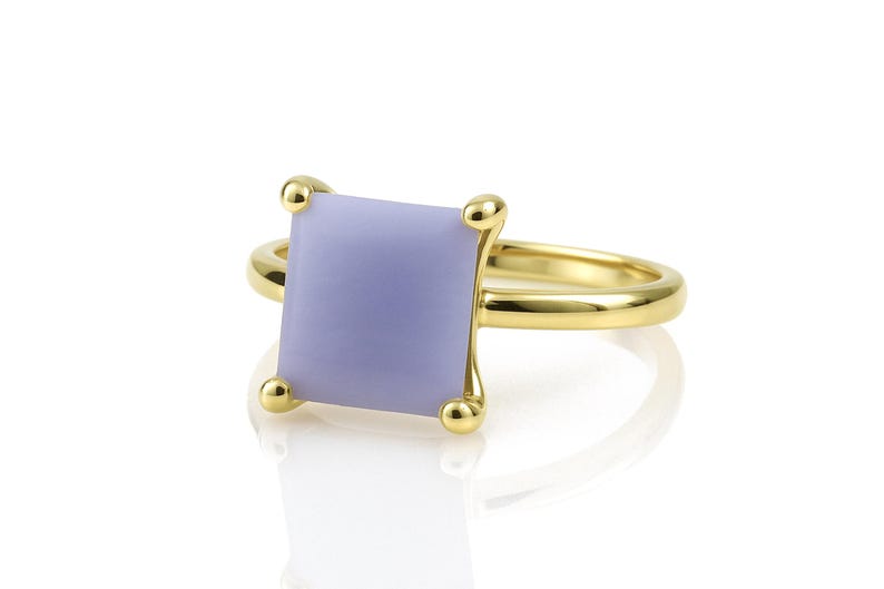 May include: A gold ring with a square, lavender-colored gemstone.