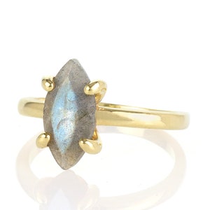 Puede incluir: Un anillo de oro con una piedra preciosa de labradorita con corte marquesa. La piedra iridiscente gris y azul est&aacute; sujeta por cuatro garras de oro. La banda del anillo es de oro pulido simple.