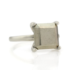 Puede incluir: Un anillo de plata con una piedra preciosa de pirita de forma cuadrada.
