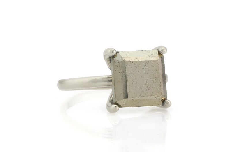 Puede incluir: Un anillo de plata con una piedra preciosa de pirita de forma cuadrada.