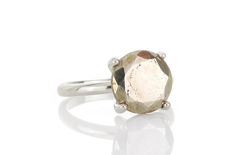 May include: A silver ring with a large, faceted, round, light brown gemstone.