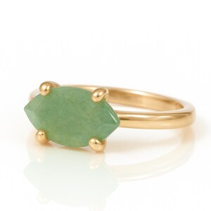 May include: A gold ring with a light green marquise-shaped gemstone.