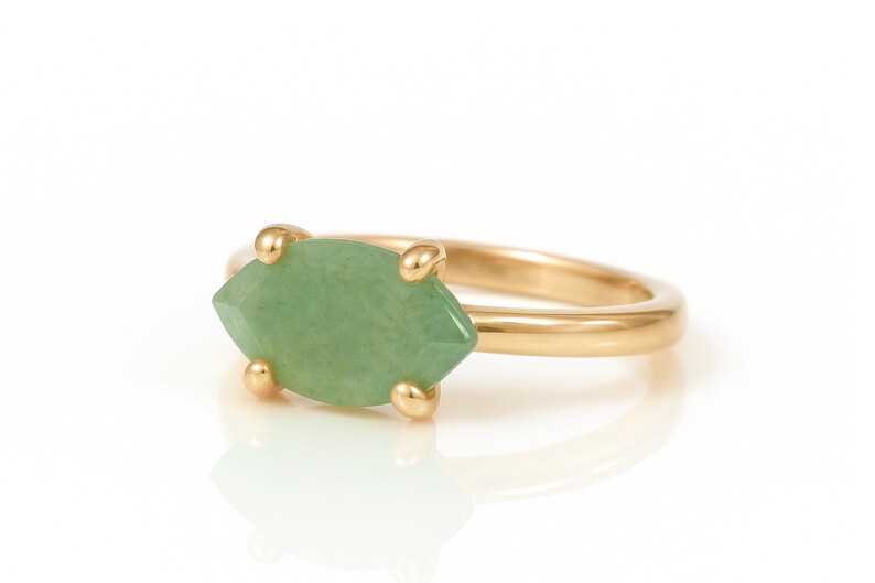 May include: A gold ring with a light green marquise-shaped gemstone.