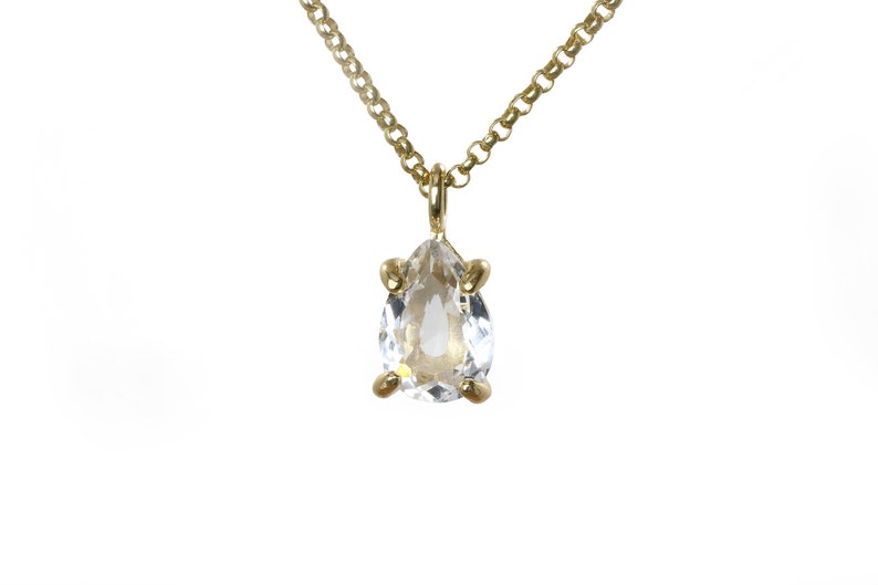 May include: A gold chain necklace with a pear-shaped clear crystal pendant.