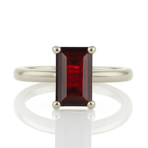 May include: A silver ring with a red rectangular gemstone set in a bezel setting.