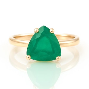 May include: A gold ring with a large, green gemstone in a triangular shape.