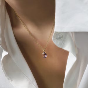 May include: A gold chain necklace with a light purple gemstone pendant.