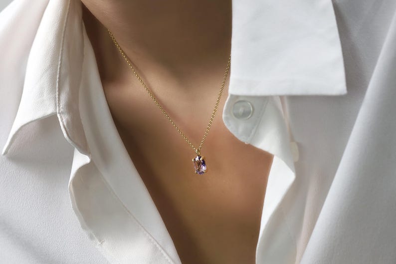 May include: A gold chain necklace with a light purple gemstone pendant.