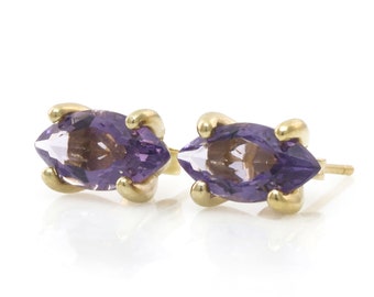 May include: A pair of gold earrings with marquise-shaped amethyst gemstones.