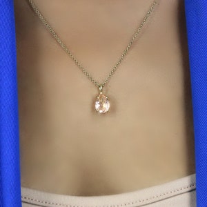 May include: A gold chain necklace with a pear-shaped pink gemstone pendant.