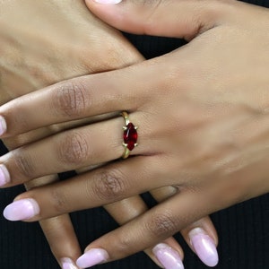 May include: A gold ring with a marquise-shaped red gemstone.