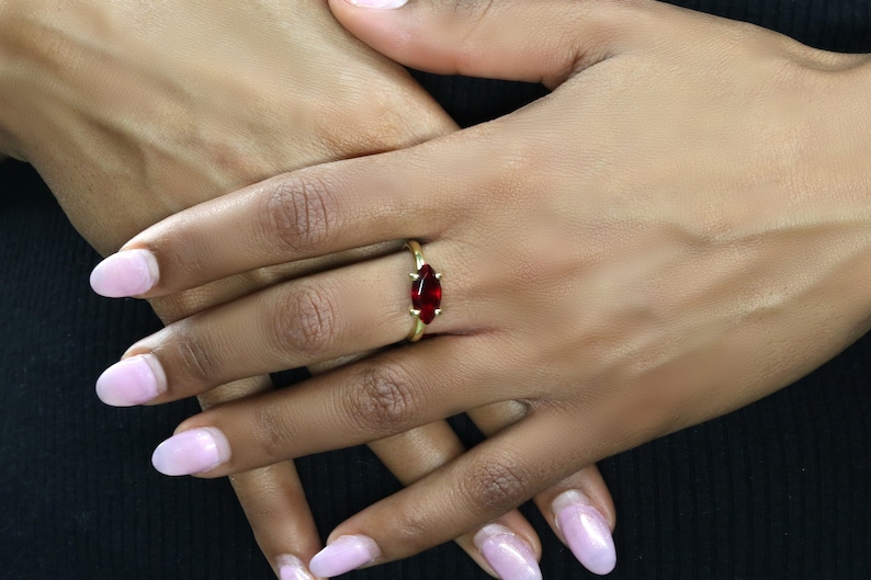May include: A gold ring with a marquise-shaped red gemstone.