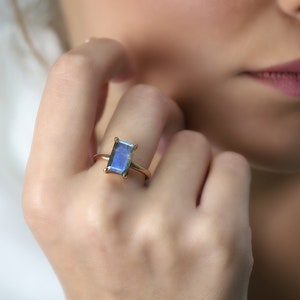 May include: A gold ring with a large, rectangular, iridescent blue gemstone.