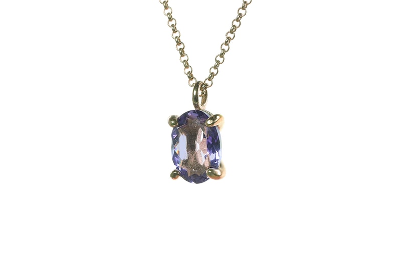 May include: A gold chain necklace with a pendant featuring a purple oval gemstone.