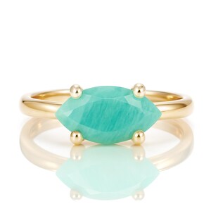 K&ouml;nnte beinhalten: Ein goldener Ring mit einem gr&uuml;nen Edelstein in Marquise-Form.