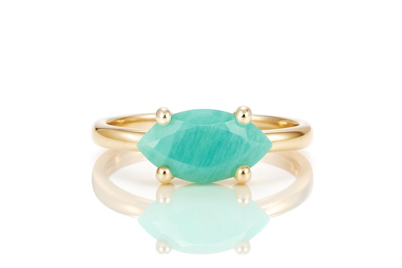 K&ouml;nnte beinhalten: Ein goldener Ring mit einem gr&uuml;nen Edelstein in Marquise-Form.