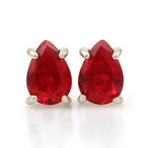 May include: A pair of silver teardrop earrings with red crystal stones.