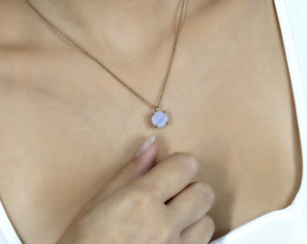 May include: A delicate gold chain necklace with a light blue agate pendant. The pendant is round and has a slightly textured surface.